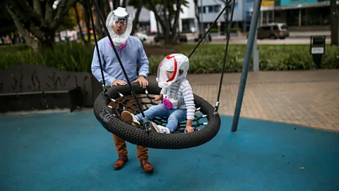 Anadolu Agency/Getty Images Man and child with anti-Covid helmets (Credit: Anadolu Agency/Getty Images)