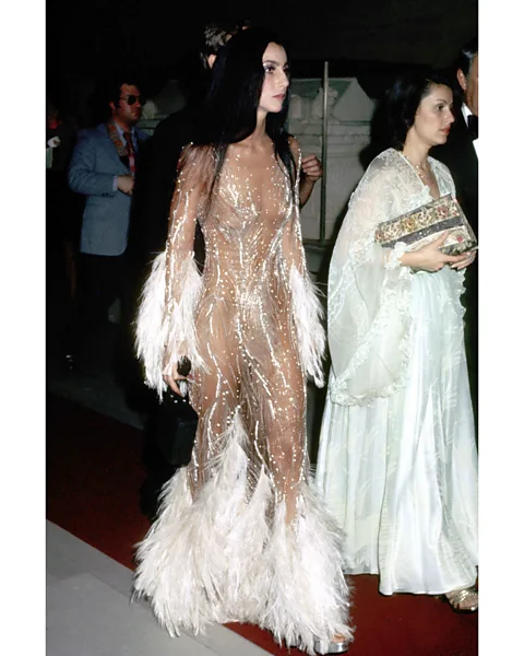 Getty Images In 1974, Cher wore a stunning, feathered, see-through dress by Bob Mackie to the Met, causing a "hullabaloo", as the designer put it (Credit: Getty Images)
