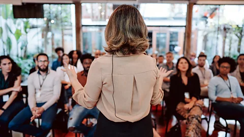 Getty Images Woman presenting lecture in front of crowd (Credit: Getty Images)