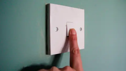 Getty Images Finger on white lightswitch against green wall 