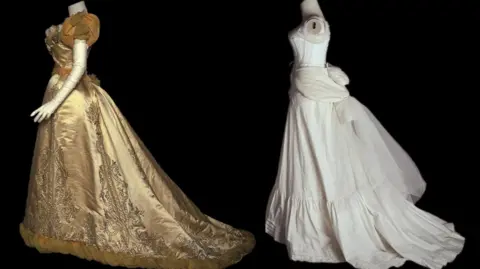Chicago History Museum/Getty Images A headless mannequin wears a golden ball gown, with bodice and full skirt, of the late Victorian period, while another wears white undergarments in the form of a corset and skirt.