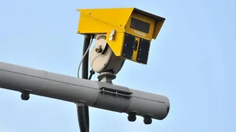 Getty Images A yellow ANPR camera connected to a grey post with blue sky in the background