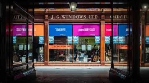 Michael Bailey The multi-coloured shop front of J.G Windows. Musical instruments can be seen through the windows.