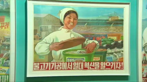 BBC A printed poster saying ‘Let’s innovate the fish industry!’ Fishing is a dominant industry of the North Korean economy. (1981)