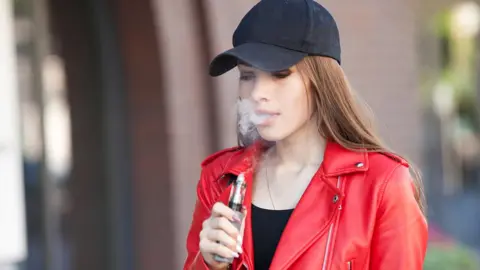 Getty Images Young woman vaping on the street