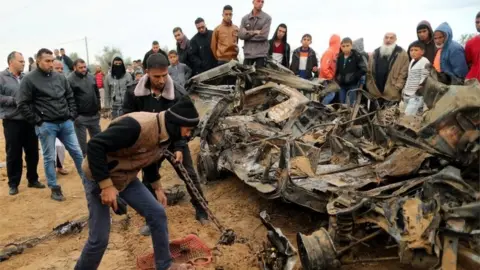 Reuters Palestinians look at wreckage of car destroyed in Israeli air strike in Khan Younis (12/11/18)