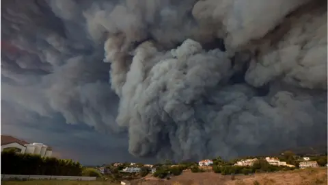 Getty Images A massive smoke plume, powered by strong winds, rises above the the Woolsey Fire