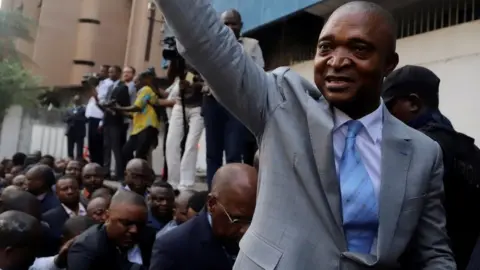 Reuters Former Congolese interior minister Emmanuel Ramazani Shadary waves to his supporters as he arrives to file his candidacy for the presidential election, at the Congo"s electoral commission (CENI) head offices at the Gombe Municipality in Kinshasa, Democratic Republic of Congo, August 8, 2018.