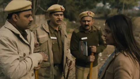Netflix A still from the series showing DCP Chaturvedi speak to three police officers
