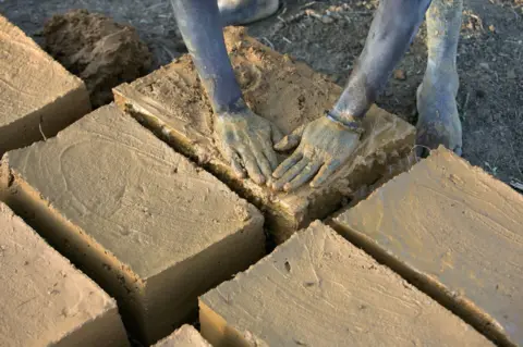 Getty Images Evariste Citegetse shapes the mud bricks she will use to build her family's home in Ruyigi, Burundi