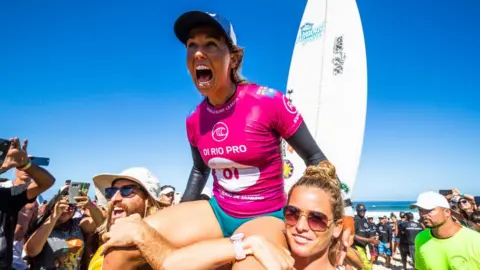 Getty Images Sally Fitzgibbons sits on top of her supporters shoulders as she celebrates her Rio Pro win