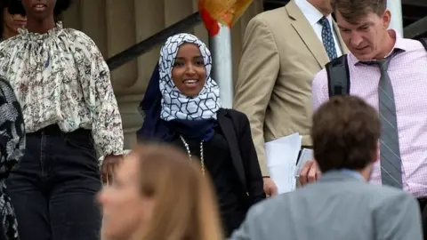 Getty Images Ilhan Omar, centre, reacts to passing of motion