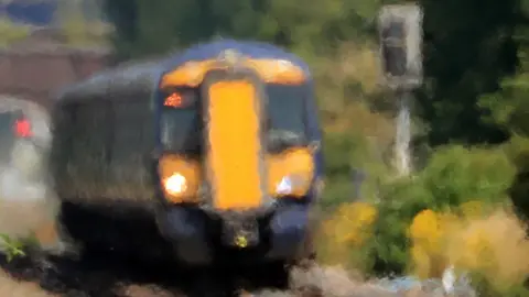 PA Media A Southeastern train passes through heat haze in Ashford, Kent