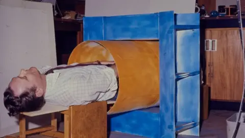 University of Nottingham Sir Peter Mansfield inside a cardboard tube