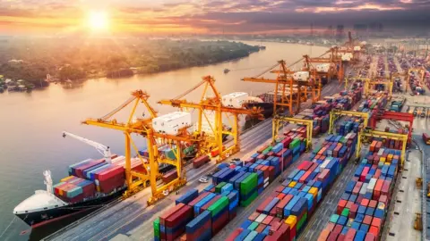 Getty Images Logistics and transportation of Container Cargo ship and Cargo plane with working crane bridge in shipyard at sunrise
