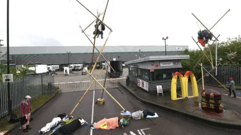 PA Media Animal Rebellion protesters suspended and attached to a bamboo structure outside a McDonalds distribution site in Hemel Hempstead