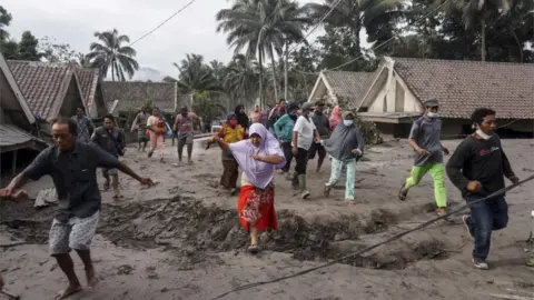 EPA People inspect their village which has been buried with volcanic ash