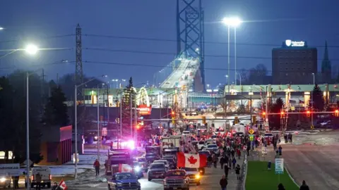 Getty Images Night falls on the Ambassador Bridge with protesters in the foreground