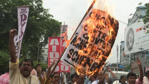 Getty Images All India Democratic Students Organization (AIDSO) members burn placards and stage protest against Agnipath recruitment scheme for central defense forces on June 18, 2022 in Kolkata, India.