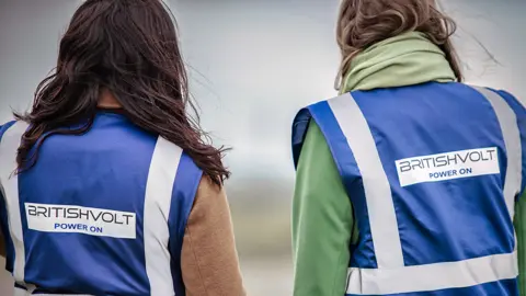 Britishvolt Workers in reflective gear look on while working outside