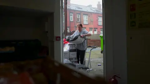 BBC Janice unloads a heavy bag of potatoes into the food hub from a delivery pallet