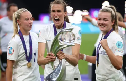 Jonathan Moscrop/Getty Images Jill Scott celebrates with the trophy along with team mates Beth Mead and Lauren Hemp