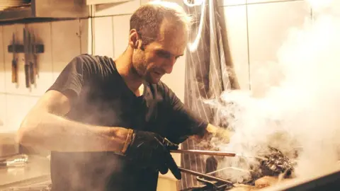 Getty Images Man working over a barbecue in a fast food restaurant