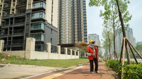 Joyce Liu/BBC A woman working as a street cleaner in China