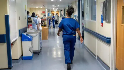 PA Media A nurse walking down a hospital corridor