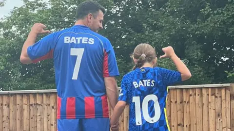Family photo Steve and Mia with their backs to the camera showing their shirt numbers
