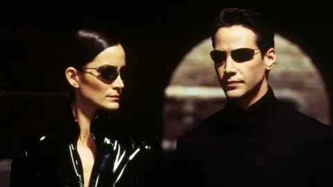 Moviestore/Shutterstock Carrie-Anne Moss and Keanu Reeves in The Matrix Reloaded