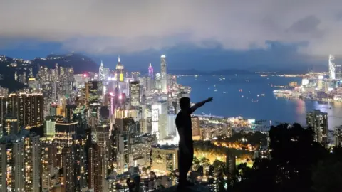 Handout Qingfeng stands in front of a lit-up Hong Kong skyline