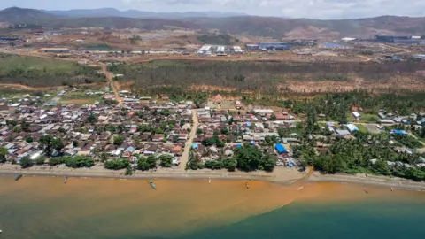Getty Images Red sediment pours from a river into the sea in the village of Kawasi in October 2022