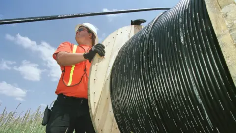 Getty Images A workman laying fibre optic cable