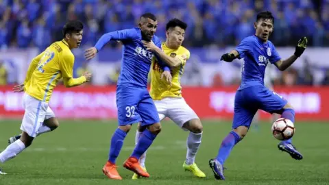 Google Shanghai Shenhua's Argentine striker Carlos Tevez (2L) fights for the ball with Yang Xiaotian (2R) of Jiangsu Suning during their Chinese Super League football match in Shanghai on March 5, 2017