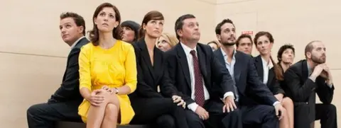 Getty Images Woman in yellow sitting next to work-mates dressed in black