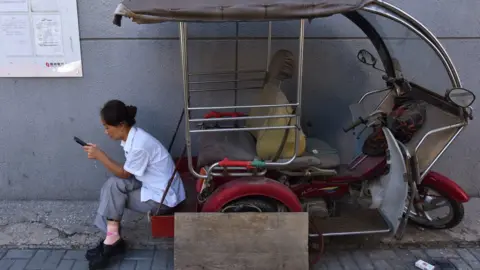 Getty Images Woman on auto-rickshaw staring at phone