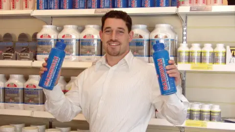 Zef Eisenberg Zef Eisenberg holding Maximuscle bottles in 2002