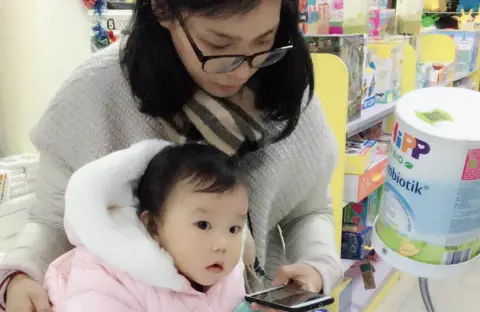 Zeng Mother uses phone to verify authenticity of baby formula
