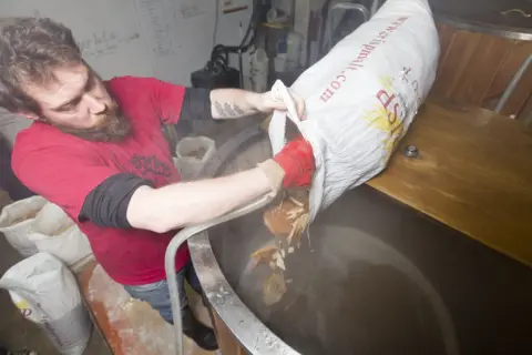 TOM MOGGACH A worker pours bread into a barrel