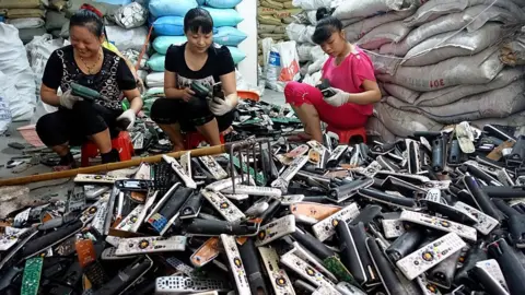Getty Images A group of women sorting through old TV remotes in Guiyu, China