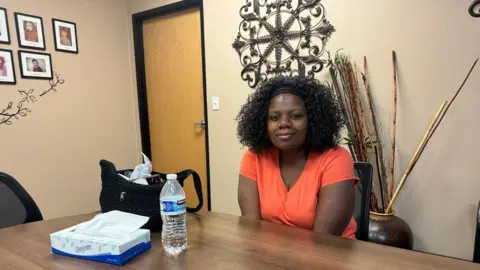 Dominic Richmond, a woman wearing an orange t-shirt, sits in the offices of Children's Cabinet, a non-profit in the Las Vegas area.