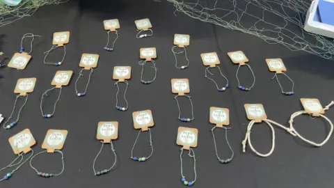 Examples of bracelets made from Lough Neagh fish nets. They are green coloured and have small beads.