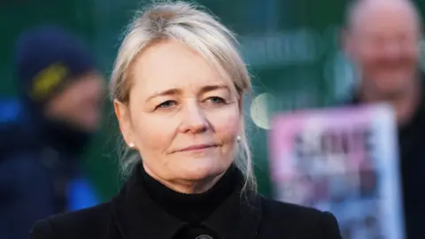 PA A photo of Sharon Graham, she is wearing a black coat, with pearl earings