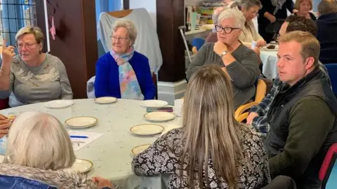 Dr James Brown and Dr Matt Ash sitting around a table with carers of people with dementia, at a support group in Essex.