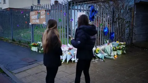 BBC Two women stood in front of floral tributes in Bristol