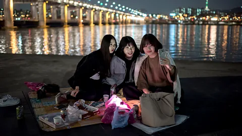 Getty Images A group of women look at a smartphone near the Han River. South Korea has the highest percentage of smartphone users in the world (Credit: Getty Images)