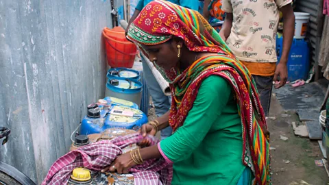 Lou Del Bello Fatima demonstrates how to carry heavy water containers by wrapping a cloth around the top for grip (Credit: Lou Del Bello)