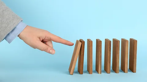 Liudmila Chernetska/Getty Images Finger pushing domino (Credit: Liudmila Chernetska/Getty Images)