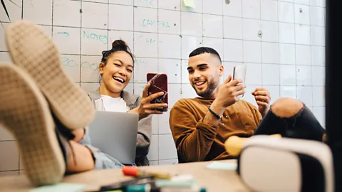 Alamy Two young workers looking at their phones